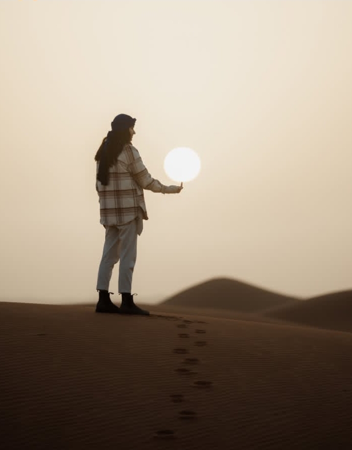 ​Solo female traveler watching the sun in the Merzouga desert dunes - Sahara adventure
